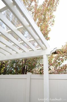 a white pergola over a fence with trees in the background