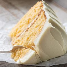 a piece of cake with white frosting and a spoon in it on top of paper