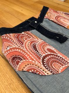 a pair of jeans sitting on top of a wooden floor next to a piece of cloth