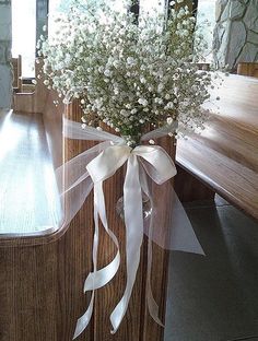 a bouquet of baby's breath sitting on top of a wooden bench next to a window