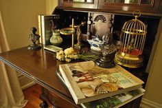 a wooden table topped with a birdcage filled with flowers and other items on top of it