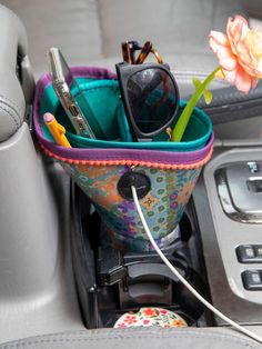 a car dashboard with a cup holder holding various items in it and a phone plugged into the charger