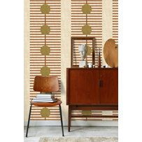 a room with a chair, mirror and wallpaper on it's sideboard