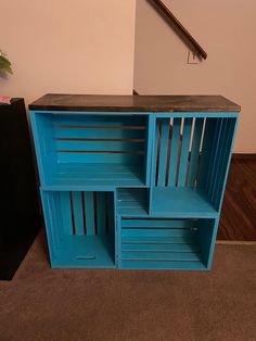 a blue shelf with three sections stacked on top of each other in front of a stair case