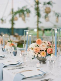 the table is set with place settings and flowers in vases on each side, along with silverware