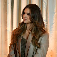 a woman standing in front of a curtain with her hands on her hips and looking off to the side