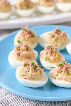 deviled eggs topped with tuna and chives on a blue plate