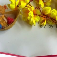 two small figurines are sitting in a boat with yellow flowers on the side