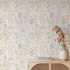 a flowery wallpaper with flowers on it and a plant in a vase next to the cabinet