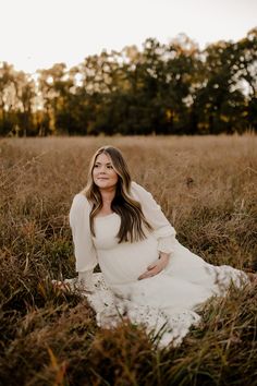 a pregnant woman sitting in tall grass