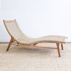 a woven chaise lounge chair sitting on top of a carpeted floor next to a white wall