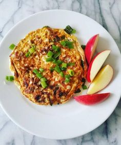 a white plate topped with an omelet and sliced apple on top of a marble counter