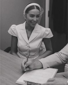 a woman sitting at a table with a pen in her hand