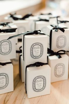 small white boxes with black ribbon tied around them on a wooden counter top, sitting next to each other