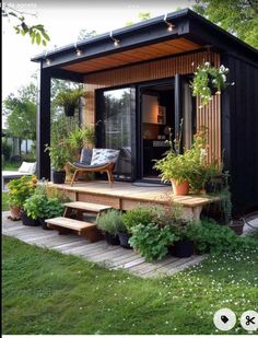 a small black house with plants on the porch