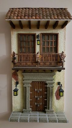 a doll house with a balcony and wooden doors