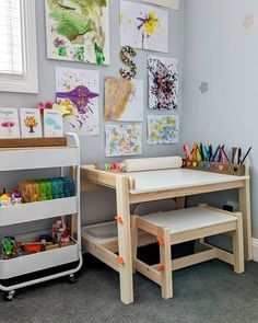 a child's room with toys and artwork on the wall, including two desks