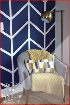 a chair with a blanket on it in front of a wall painted blue and white