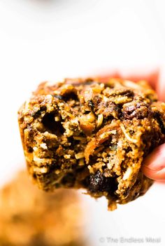 a hand holding up a cookie with nuts and raisins on it's side