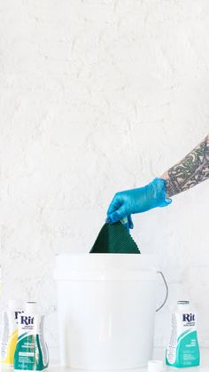 a man in blue gloves and rubber gloves cleaning a white bucket with green cloths