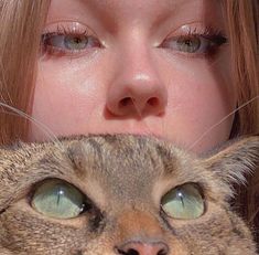 a close up of a person with a cat in front of her face and one eye open