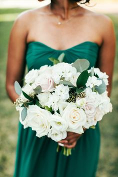 a woman in a green dress holding a white bouquet