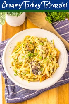 creamy turkey tetrazzini with mushrooms and parsley in a white bowl on a wooden table