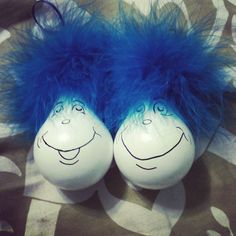 two white balls with blue hair on them sitting on a patterned table cloth next to each other