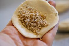 a hand holding a small cracker with some kind of food on top of it