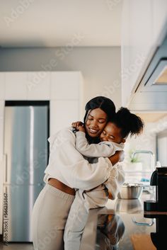 two women hugging each other in the kitchen