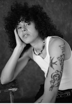 a black and white photo of a woman with tattoos on her arm