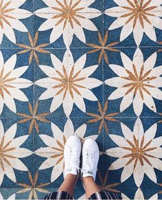 a person standing in front of a blue and white tile floor with flowers on it