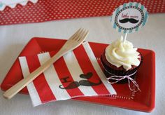 a red plate topped with a cupcake and a fork