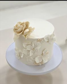 there is a white cake with flowers on the top and bottom layer, sitting on a plate