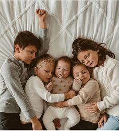 a group of children laying on top of each other in the middle of a bed