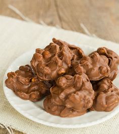 a white plate filled with chocolate covered cookies on top of a wooden table next to a napkin