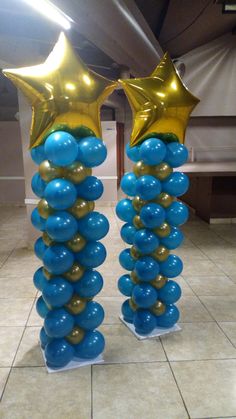 two tall blue and gold balloons with stars on them in the middle of a tiled floor