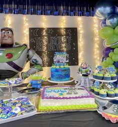 a table topped with cake and balloons next to a giant toy buzz lightyear figure