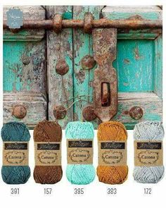 four balls of yarn sitting next to an old wooden door with rusted metal handles