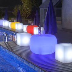 an outdoor swimming pool with illuminated stools and umbrellas