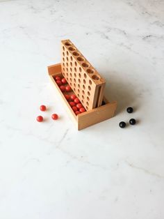 a wooden box filled with red and black balls on top of a white marble counter