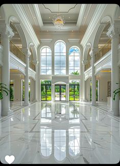 a large white building with many windows and columns on the ceiling, in front of a chandelier