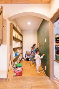 two children are standing in front of the bookshelf and writing on the wall