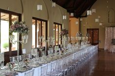 a long table is set up for a formal function with tall centerpieces and flowers