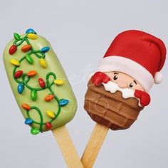 two pops decorated like santa claus and an ice cream sundae on wooden sticks with christmas lights