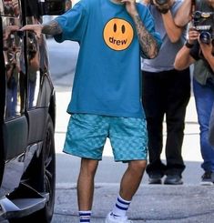 a man in blue shirt and shorts standing next to a car