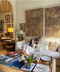 a living room filled with furniture and paintings on the wall above it's coffee table