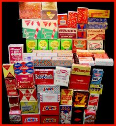 many different types of candy boxes stacked on top of each other in front of a black background