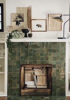 a fireplace with green tiles and pictures on the wall above it in a living room