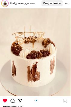 a white cake with chocolate frosting and decorations on top, sitting on a plate